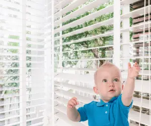 Toddler reaching for a window blind cord