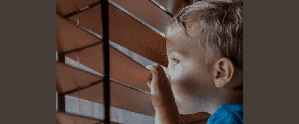 Child looking through window blinds